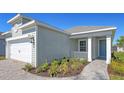 Exterior showing light-green siding, a two-car garage and the front entrance of this single story home at 10054 Cross River Trl, Parrish, FL 34219