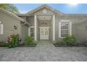 Inviting front entrance with a stylish gray facade, decorative columns, and manicured garden beds at 1693 Landings Ln, Sarasota, FL 34231