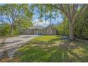 Lush front yard with mature trees and a glimpse of the charming home, creating a serene setting at 1693 Landings Ln, Sarasota, FL 34231