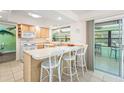 Open kitchen with white countertop seating, tile floors, and sliding door access to an outdoor space at 18399 Burkholder Cir, Port Charlotte, FL 33948