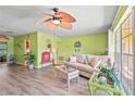 Bright living room with a ceiling fan, cozy seating, and a large window offering natural light at 18399 Burkholder Cir, Port Charlotte, FL 33948