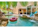 Tropical backyard oasis with private pool, rock waterfall, outdoor dining, and seamless indoor-outdoor living at 4001 5Th Ave, Holmes Beach, FL 34217