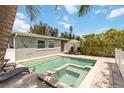Beautiful in-ground pool and jacuzzi are surrounded by lush vegetation and patio with seating at 424 62Nd St, Holmes Beach, FL 34217