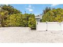 Gravel drive with white picket fence and gate surrounded by mature bushes and trees at 424 62Nd St, Holmes Beach, FL 34217