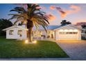 Inviting single-story home with well-lit exterior, mature palm tree, and manicured lawn at 527 Key Royale Dr, Holmes Beach, FL 34217