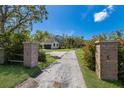 Long driveway leading to a beautiful two-story home, framed by brick pillars and vibrant flowering bushes at 5307 22Nd W Ave, Bradenton, FL 34209