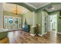 Elegant foyer featuring hardwood floors, a decorative chandelier, and neutral paint with green accent walls at 5329 Trails Bend Ct, Sarasota, FL 34238