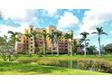 Exterior view of well-maintained condo building overlooking lush green lawn and tranquil pond at 611 Riviera Dunes Way # 107, Palmetto, FL 34221