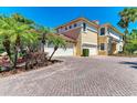 Mediterranean home exterior featuring a brick driveway, tropical landscaping, and a two-car garage at 9429 Discovery Ter # 102B, Bradenton, FL 34212