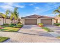 Lovely home with a three-car garage, paver driveway, and manicured landscaping, showcasing great curb appeal at 12091 Amica Loop, Venice, FL 34293
