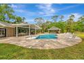 Outdoor living with a sparkling pool, adjacent covered bar area, lounge chairs and lush landscaping at 1240 Fox Creek Dr, Sarasota, FL 34240
