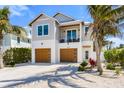 Charming two-story home with a balcony and two-car garage, surrounded by lush landscaping and palm trees at 140 Crescent Dr, Anna Maria, FL 34216