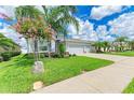 Beautiful home featuring a lush green lawn, decorative trees, and a long concrete driveway at 15612 Trinity Fall Way, Bradenton, FL 34212