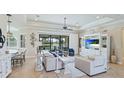 Elegant living room featuring tray ceilings, tile floors, and expansive sliding glass doors at 20114 Uffizi Ct, Venice, FL 34293
