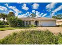 Charming single-story home with a barrel tile roof, lush landscaping, and a circular driveway at 412 Giovanni Dr, Nokomis, FL 34275