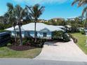 Inviting coastal home with light blue exterior, silver metal roof, paver driveway, and lush tropical landscaping at 5608 Holmes Blvd, Holmes Beach, FL 34217