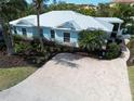 Attractive home featuring mature landscaping, light blue siding, impact windows, and a beautiful paver driveway at 5608 Holmes Blvd, Holmes Beach, FL 34217