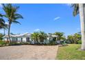 Charming single-story home featuring a paver driveway, tropical landscaping, and a light-colored exterior paint at 5608 Holmes Blvd, Holmes Beach, FL 34217