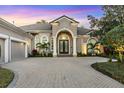 Elegant home showcasing a beautiful paver driveway leading to a grand arched entrance with striking double doors at 7257 Greystone St, Lakewood Ranch, FL 34202