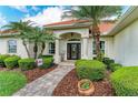 Welcoming front entrance with a tiled walkway, lush landscaping, and a charming doorway, framed by decorative columns at 22333 Panther Loop, Bradenton, FL 34202