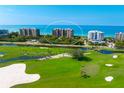 Aerial view of luxury condos overlooking a lush golf course and the ocean at 435 L Ambiance Dr # H902, Longboat Key, FL 34228