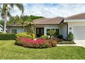 Well-maintained home exterior featuring colorful flower beds and lush tropical landscaping at 4444 Highland Oaks Cir, Sarasota, FL 34235