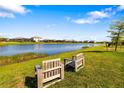 Scenic backyard view with a tranquil lake, lush grass, and relaxing chairs, perfect for enjoying nature at 5235 Coral Reef Way, Bradenton, FL 34211