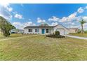 Inviting single-story home featuring a well-kept lawn, vibrant flower beds, and a bright blue front door at 7002 Primm Pl, North Port, FL 34287