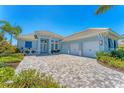 Beautiful light blue house showcasing a three-car garage and brick driveway at 16436 Daysailor Trl, Lakewood Ranch, FL 34202