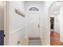Bright foyer with coat hooks, arched transom window and views of the hardwood flooring beyond at 16620 Fairbolt Way, Odessa, FL 33556