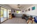 Cozy living room featuring neutral carpeting, modern ceiling fan, and sliding door to screened patio at 1770 Lake Pl # 1770D, Venice, FL 34293