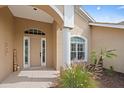 Home featuring a tiled front porch, well-maintained landscaping, and a welcoming front door with sidelights at 1975 White Feather Ln, Nokomis, FL 34275