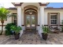 Elegant front entrance with decorative glass doors, stylish columns, and lush landscaping, creating a welcoming curb appeal at 2629 Rolling Rd, North Port, FL 34288