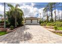 Spacious two-car garage with a long paver driveway, complemented by green landscaping and beautiful greenery at 2629 Rolling Rd, North Port, FL 34288