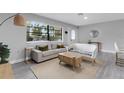Cozy living room featuring neutral-toned furnishings, a jute rug, and plenty of natural light from a large window at 3857 Woodrow Ridge St, Sarasota, FL 34233