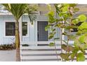 Close-up of the home's entrance and front porch, framed by lush greenery and a palm tree at 4111 Rockefeller Ave, Sarasota, FL 34231