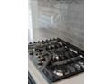 Close-up of a stainless steel gas stovetop with sleek black grates and metallic knobs at 4240 Pond Brook Ct, Bradenton, FL 34211