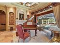 Elegant room with a fireplace, piano, and a view of the pool at 7580 Preservation Dr, Sarasota, FL 34241
