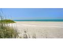 A scenic beach view with white sand meeting the tranquil, turquoise ocean under a clear blue sky at 845 Benjamin Franklin Dr # 104, Sarasota, FL 34236