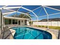 Sparkling screened-in pool with clear blue water, a paver deck, and a view of the manicured backyard at 923 Dawn St, Venice, FL 34285
