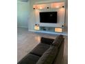 Relaxing living room with large flat-screen TV, custom wall shelving, and cozy couch seating at 10668 Lake Montauk Dr, Riverview, FL 33578