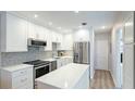 Updated kitchen features stainless steel appliances, white cabinets, tile backsplash, and large island at 117 7Th N St # 14, Bradenton Beach, FL 34217
