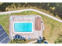 Aerial view of community pool surrounded by lounge chairs, lush landscaping, and walking path at 117 7Th N St # 14, Bradenton Beach, FL 34217