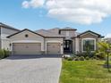 Beautiful exterior elevation with a three-car garage, paver driveway, stone accents and lush landscaping at 15104 Blue Bay Ter, Lakewood Ranch, FL 34211