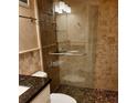 Beautiful bathroom with modern walk-in shower with pebble floor and glass door, complemented by granite countertops at 1603 Gulf Dr N # 6, Bradenton Beach, FL 34217