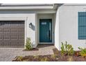 Inviting home entrance with a teal front door, stone walkway, and modern exterior lighting at 16097 Old Fox Trl, Port Charlotte, FL 33953