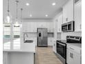 Modern kitchen with white cabinets, stainless steel appliances, and pendant lighting over the island at 16097 Old Fox Trl, Port Charlotte, FL 33953