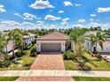 Beautiful home with a red brick driveway and tropical landscaping, including palm trees and lush green grass at 17714 Northwood Pl, Bradenton, FL 34202