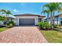 Charming home featuring a red brick driveway, gray garage door, and manicured landscaping with lush bushes at 17714 Northwood Pl, Bradenton, FL 34202