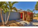 Close up view of the house's main entryway with a red door and lush landscaping at 448 58Th St, Sarasota, FL 34243